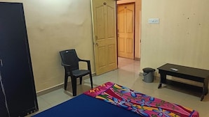 A room with a bed, a chair, a desk, and a trash bin. - Hotel Bindusagar (Bhubaneshwar)