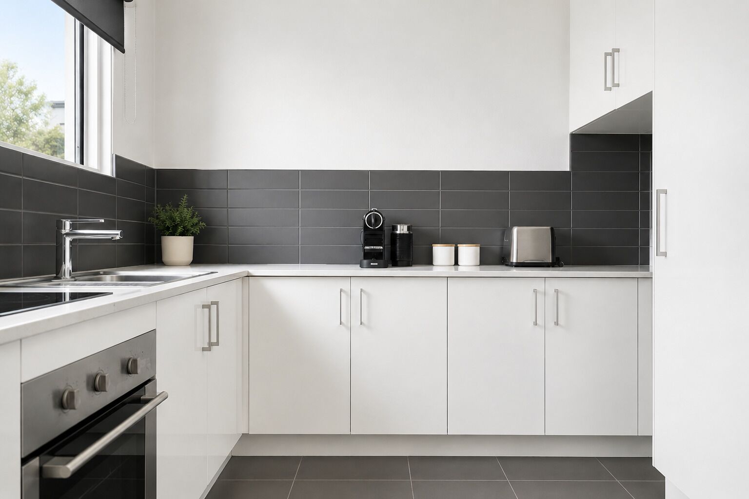 Eine moderne Küche mit weißen Schränken, einer Edelstahlspüle, einer Kaffeemaschine und einem Toaster.
