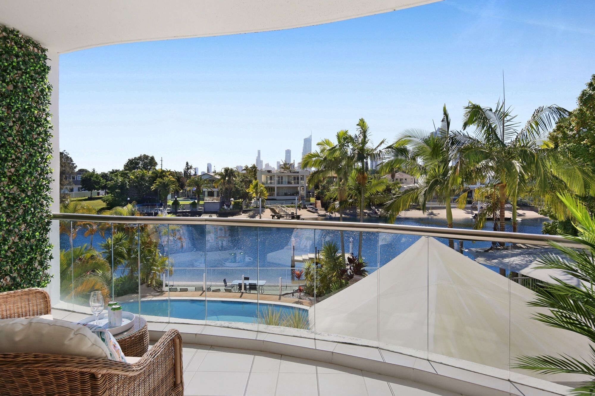 A pool area with a view of a cityscape, including palm trees and a building with a white facade.