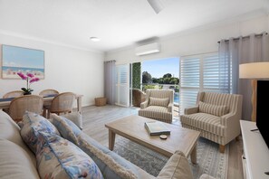 A spacious living room with a sofa, armchairs, a coffee table, and a dining area with chairs and a table. - Tranquil Waterfront Retreat | Broadbeach Waters (Broadbeach Waters)