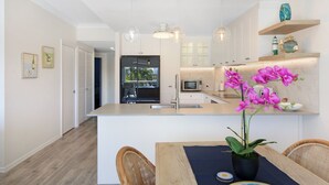 A modern kitchen with white cabinetry, a central island, and pendant lighting. - Tranquil Waterfront Retreat | Broadbeach Waters (Broadbeach Waters)