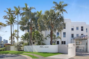 A white building with a sign reading 'ARC RESORT' and palm trees in front. - Tranquil Waterfront Retreat | Broadbeach Waters (Broadbeach Waters)