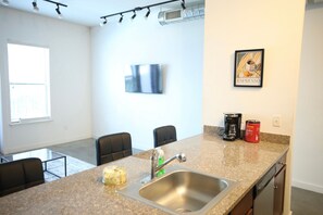 A modern kitchen with a granite countertop, stainless steel sink, and a coffee maker.