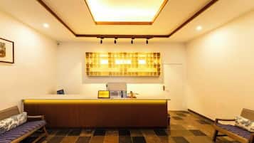 A reception area with a check-in counter, a reception desk, and seating arrangements.