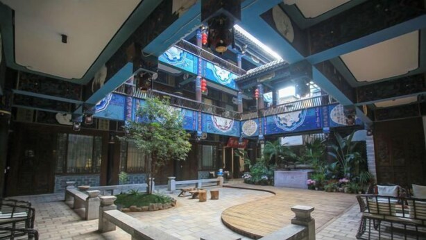 An indoor courtyard with a central seating area, surrounded by stone benches and tables, and a decorative ceiling with blue patterns. - Huiyuanlou Inn (Jianshui Ancient City Zhujia Garden Branch) (Jianshui)