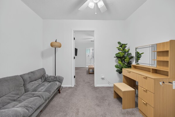 A modern living room with a grey sofa, a wooden cabinet, and a plant.