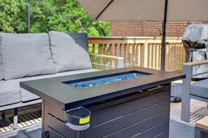 Ein moderner Außenbereich mit Metalltisch und -stühlen, einer gepolsterten Bank und einem Holzterrasse.