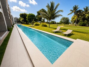 A swimming pool with clear blue water, surrounded by a tiled deck, and two lounge chairs. - Coral Juliette •Luxury PH in Cocotal • Pool • BBQ (Punta Cana)