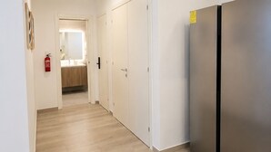 Ein Flur mit Holzboden, weißen Wänden und einem Edelstahl-Kühlschrank.