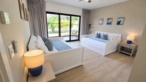 A modern hotel room with a bed, a sofa, a lamp, and a view of the outdoors. - Coral Juliette •Luxury PH in Cocotal • Pool • BBQ (Punta Cana)