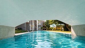 Ein Schwimmbad mit Blick auf ein Gebäude und Bäume im Hintergrund.