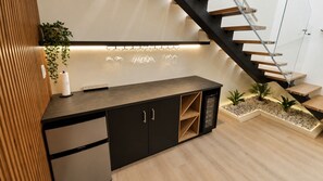 Una cuina moderna amb un viner integrat, un taulell de fusta i una escala amb barana de vidre.