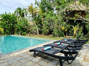 A poolside area with lounge chairs and a thatched-roof structure.