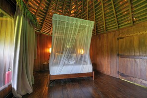 Una habitación de madera con una cama bajo dosel, paredes de madera y techo inclinado.