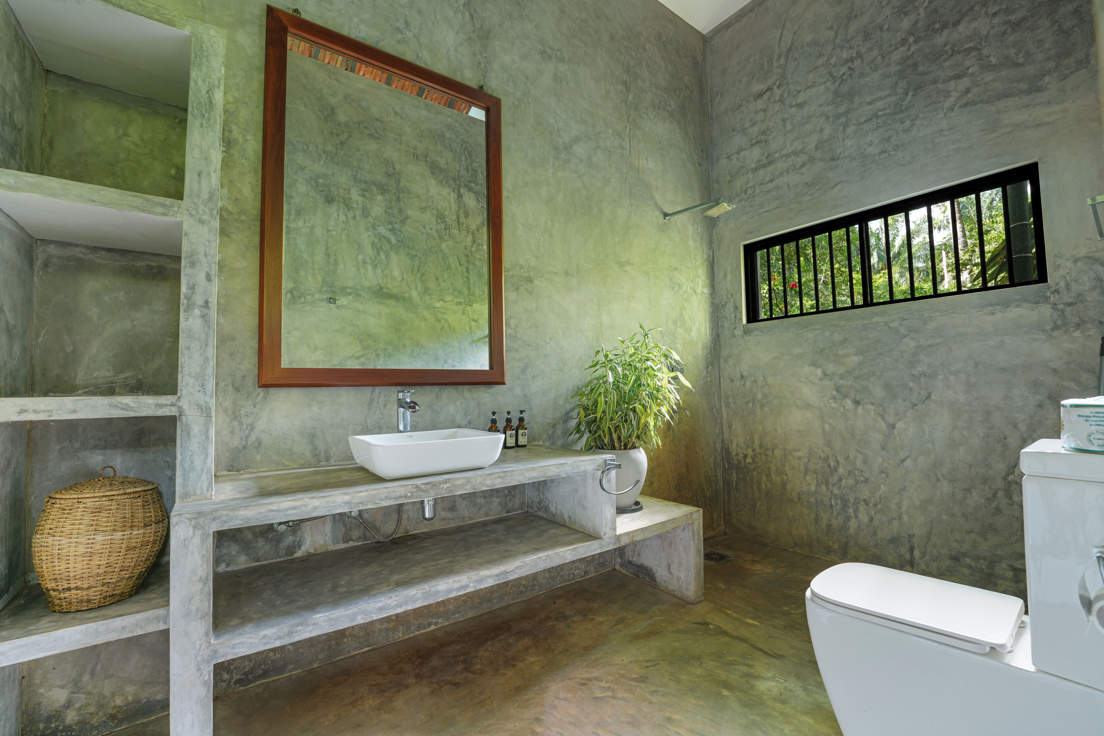 A bathroom with a white sink, a mirror, a potted plant, and a toilet.