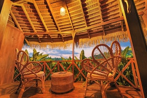 A wooden veranda with wicker furniture and a view of lush greenery.