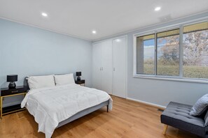 A bedroom with a bed, bedside tables, a wardrobe, and a window with blinds. - Family-Friendly 3-Bed House in Kambah (Kambah)