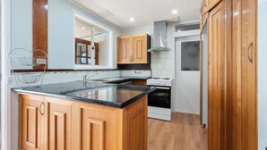 A kitchen with wooden cabinets, a granite countertop, a stainless steel range hood, and a built-in oven. - Family-Friendly 3-Bed House in Kambah (Kambah)