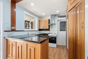 A kitchen with wooden cabinets, a granite countertop, a stainless steel range hood, and a built-in oven. - Family-Friendly 3-Bed House in Kambah (Kambah)