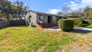 A single-story house with a front porch, a staircase leading to the entrance, and a well-maintained lawn. - Family-Friendly 3-Bed House in Kambah (Kambah)