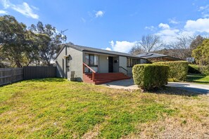 A single-story house with a front porch, a staircase leading to the entrance, and a well-maintained lawn. - Family-Friendly 3-Bed House in Kambah (Kambah)