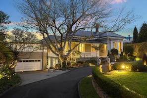 A two-story house with a garage, a well-maintained lawn, and a large tree in the front yard.