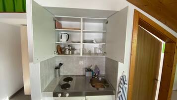 A compact kitchen with a stove, sink, and storage cabinets.