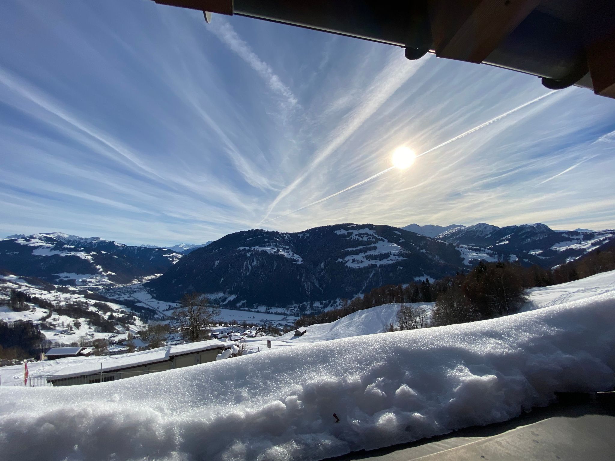 A snowy mountain landscape with a clear sky and the sun shining.