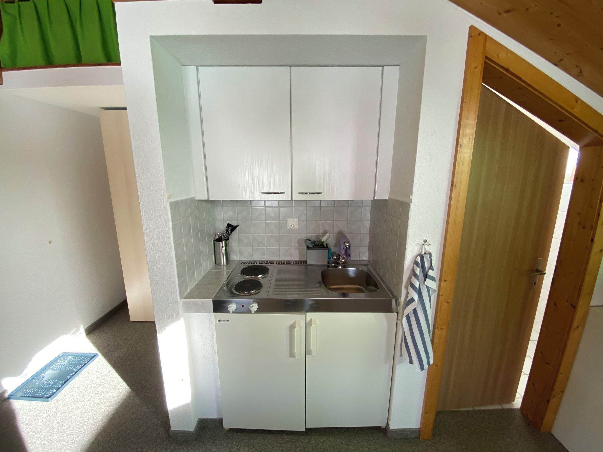 A compact kitchen with white cabinets, a sink, and a stove.