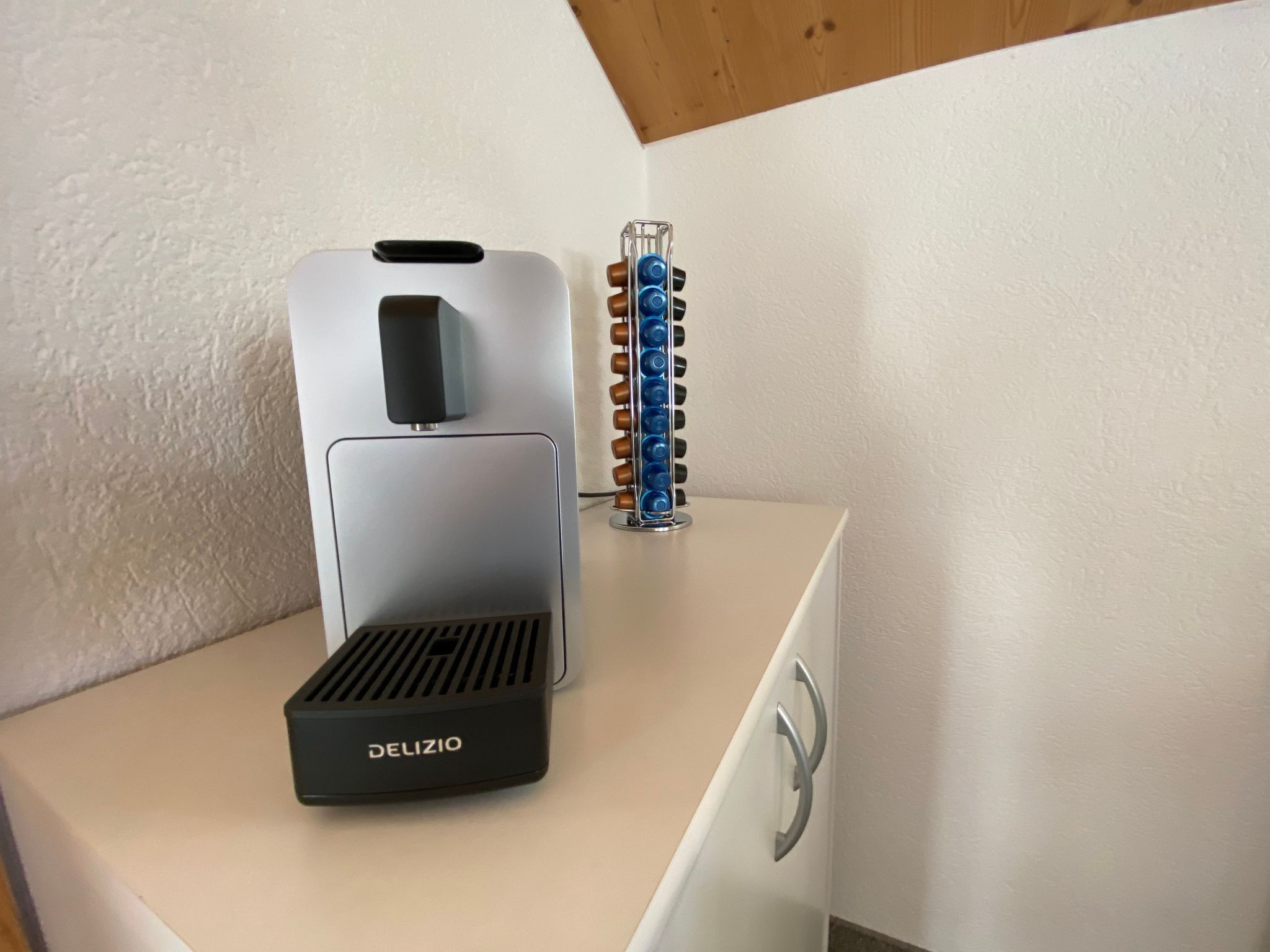 Eine Delizio-Espressomaschine steht auf einer weißen Arbeitsplatte, daneben ein metallener Kaffeemühle.