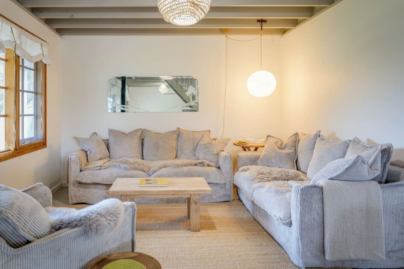 Een woonkamer met een zithoek, een salontafel en een kroonluchter.