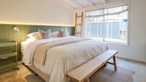 Ein Schlafzimmer mit Bett, Nachttisch, Bank und einem Fenster mit Blick.