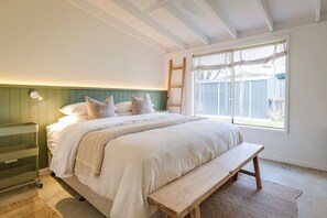 Une chambre à coucher comprenant un lit, une table de chevet, un banc et une fenêtre donnant sur un paysage agréable.