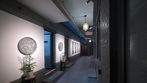 A hallway with a meeting room door, a potted plant, and a fire extinguisher.