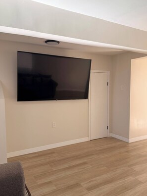 Ein Zimmer mit Flachbildfernseher an der Wand, einer Tür und Holzböden.