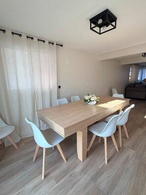 Un coin repas avec une table en bois, six chaises et un vase à fleurs.