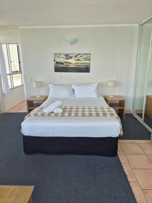 Quarto de hotel com uma cama, duas mesas de cabeceira, um quadro e um espelho grande.