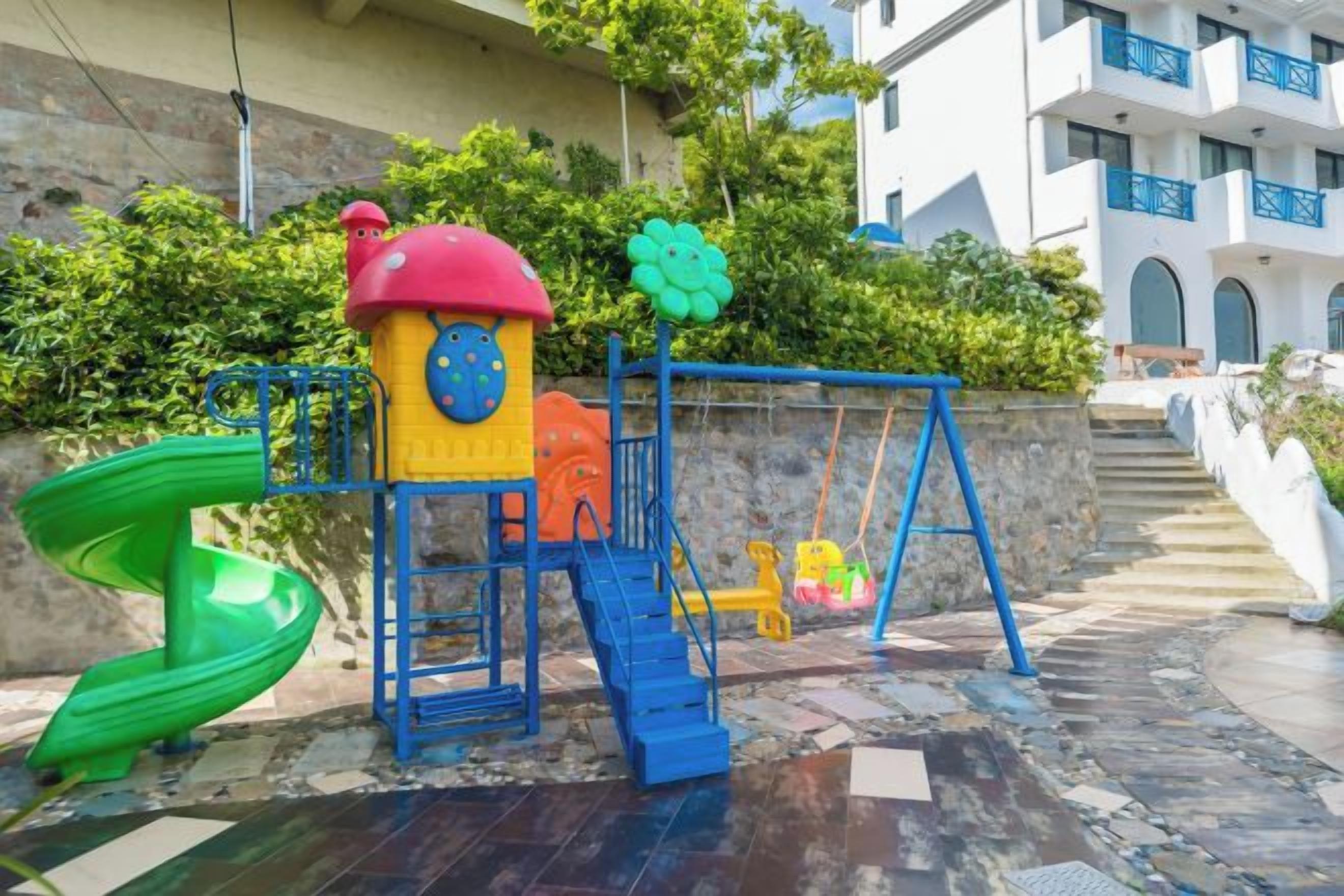 A playground with a slide, climbing structure, and swing set.
