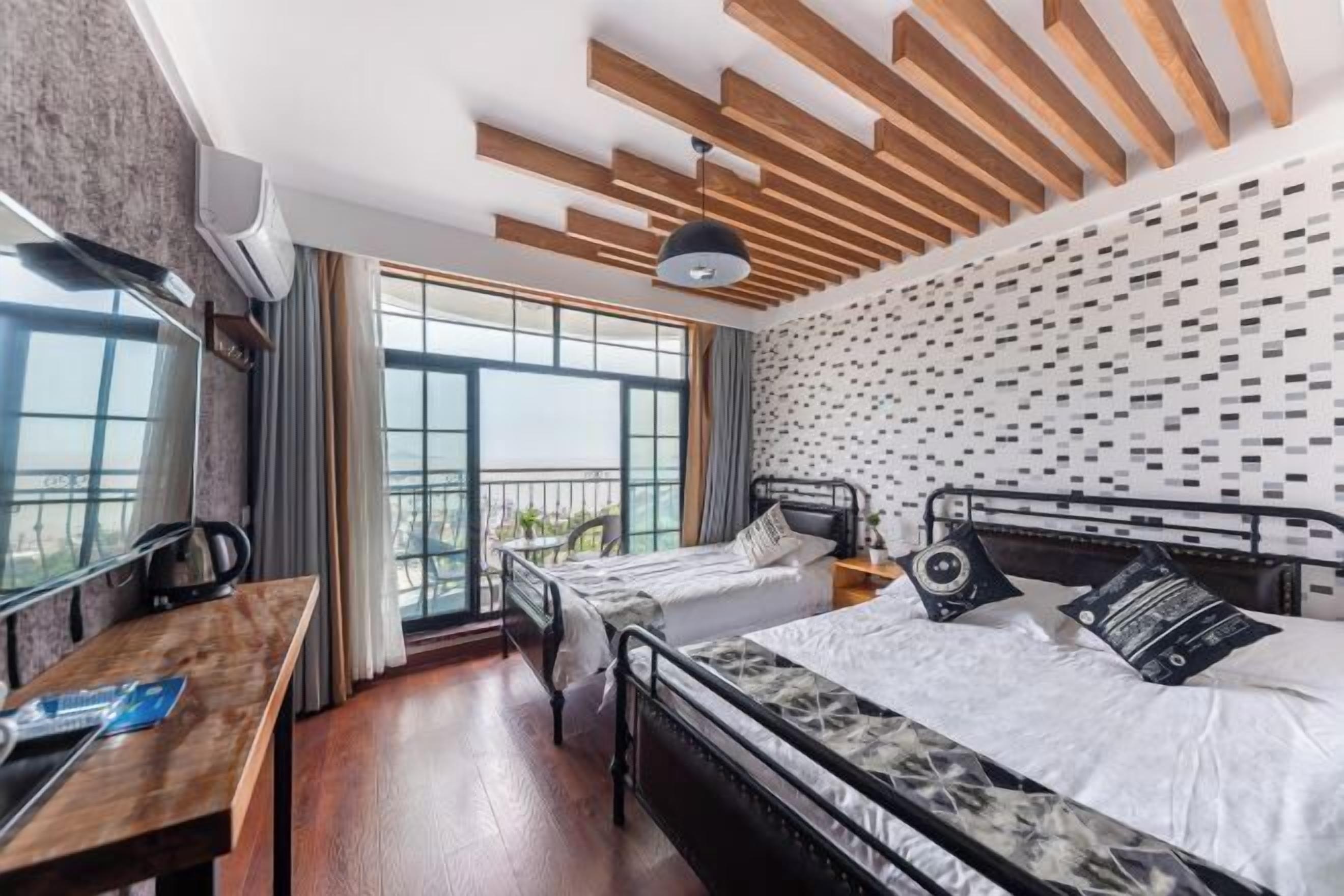 Un dormitorio con una cama, un escritorio y vistas a través de amplias ventanas.
