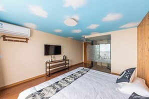 Quarto com cama, televisão, mesa de cabeceira e janela com vista.