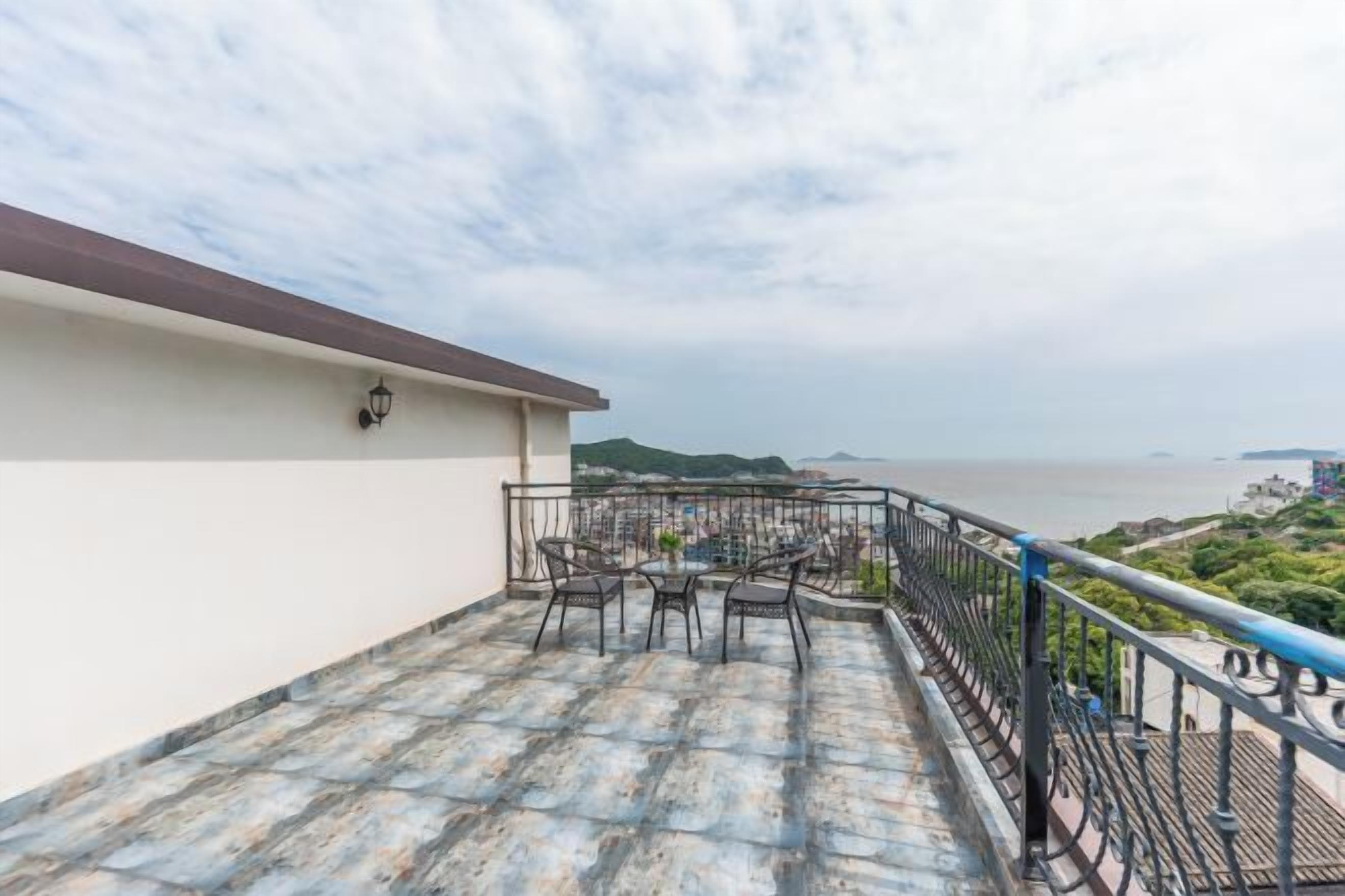 A rooftop terrace with outdoor seating and a view of the sea.
