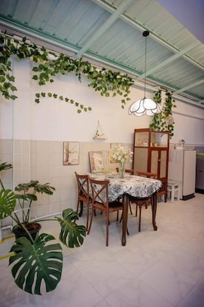 Een eethoek met een tafel, stoelen en hangplanten.