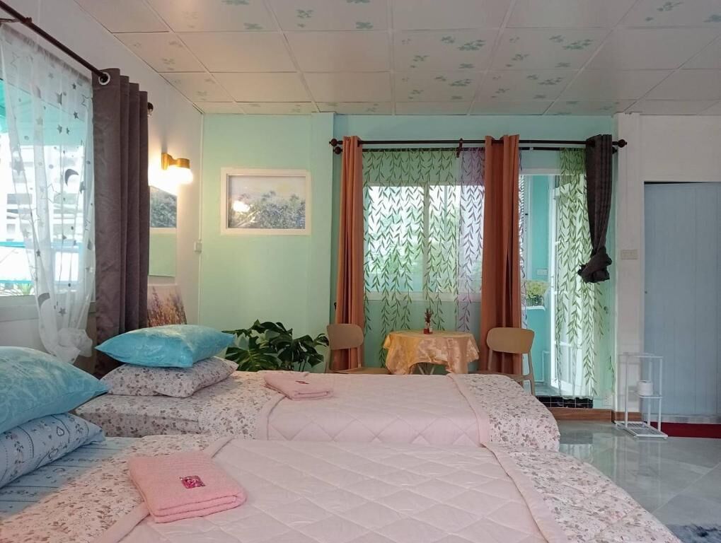 Una camera d'albergo con un letto, un tavolo, sedie, una finestra con tende e una porta.