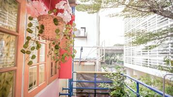 A balcony with a red wall, a wicker basket with hanging plants, and a blue railing.