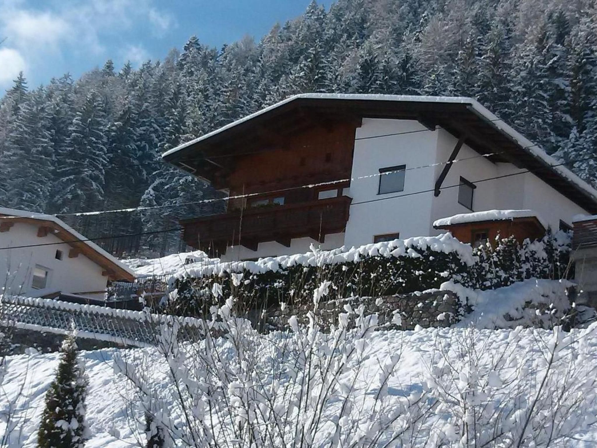 A chalet with a sloped roof, wooden balcony, and snow-covered surroundings.