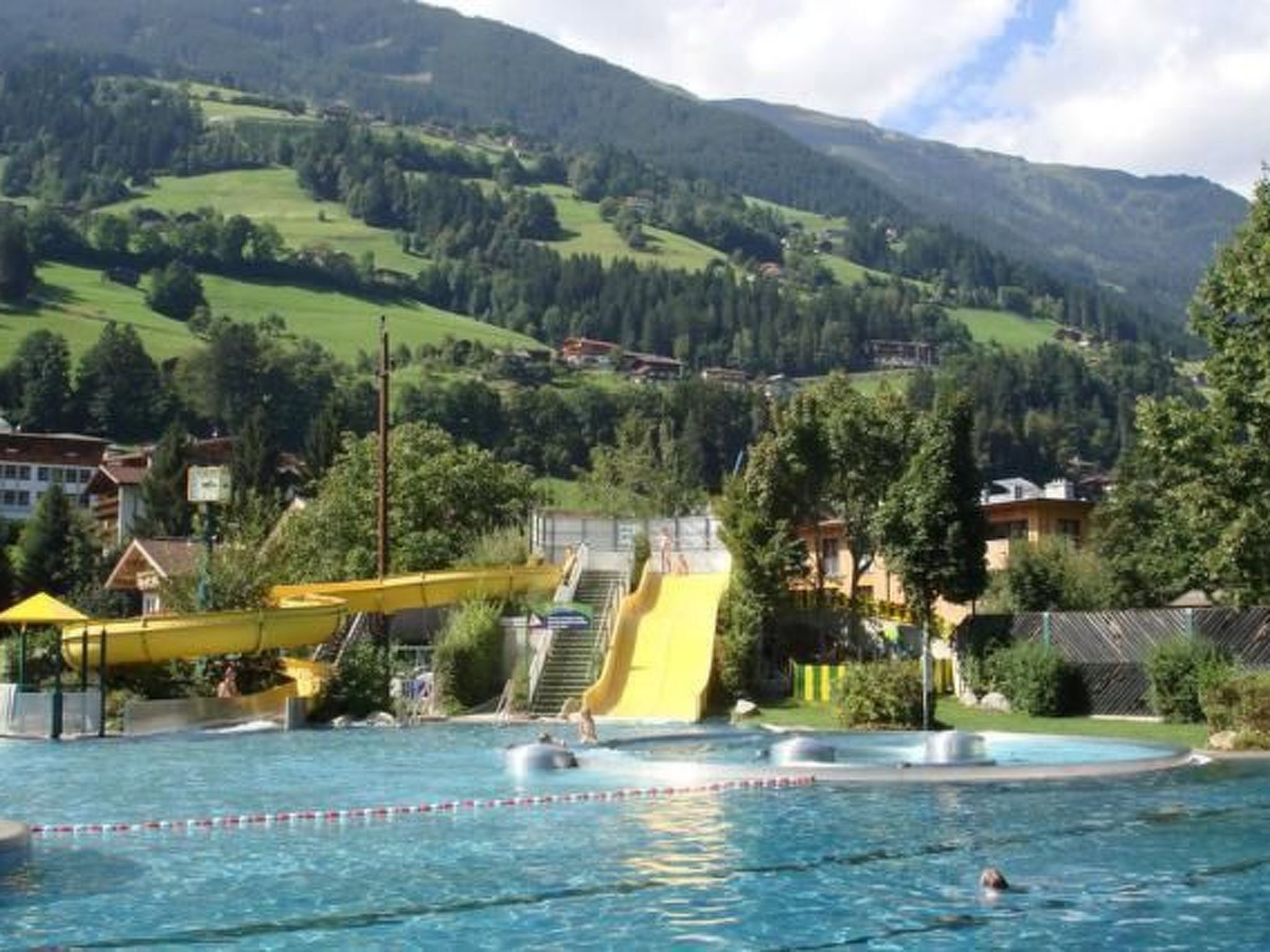 A swimming pool with a water slide and a view of a mountainous landscape.