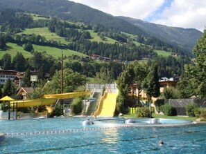 A swimming pool with a water slide and a view of a mountainous landscape. - Zuppinger by Interhome (Mayrhofen)