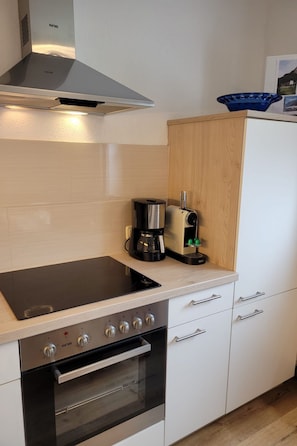 Une cuisine moderne équipée d’une cuisinière, d’un four et d’une machine à café intégrés.