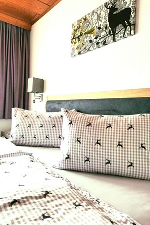 A hotel room with a bed, checkered pillows, a wall-mounted lamp, and a floral-patterned artwork. - Zuppinger by Interhome (Mayrhofen)