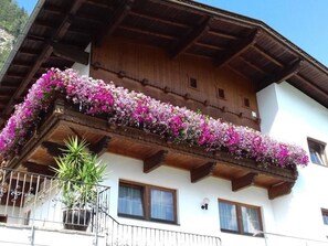 A building with a wooden balcony adorned with flowers, a metal railing, and a potted plant. - Zuppinger by Interhome (Mayrhofen)